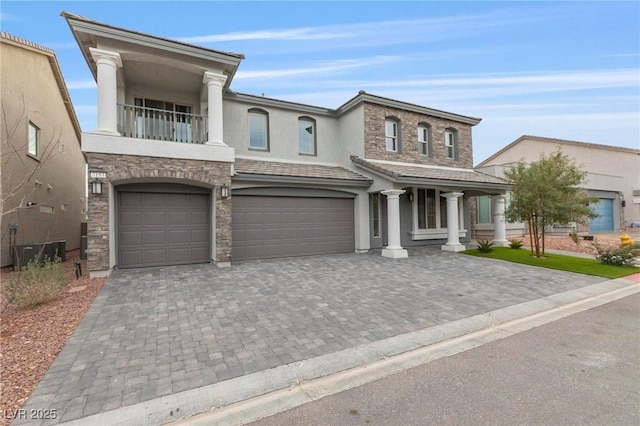 view of front of property with decorative driveway, stucco siding, a balcony, a garage, and stone siding