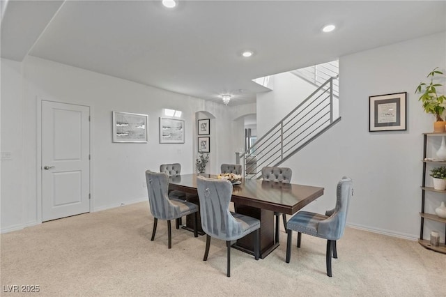 dining area with arched walkways, light carpet, baseboards, and recessed lighting