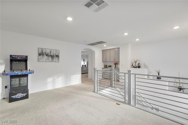 interior space featuring arched walkways, visible vents, light carpet, and recessed lighting