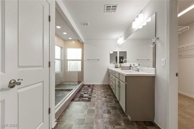 bathroom with a walk in shower, a sink, visible vents, baseboards, and double vanity