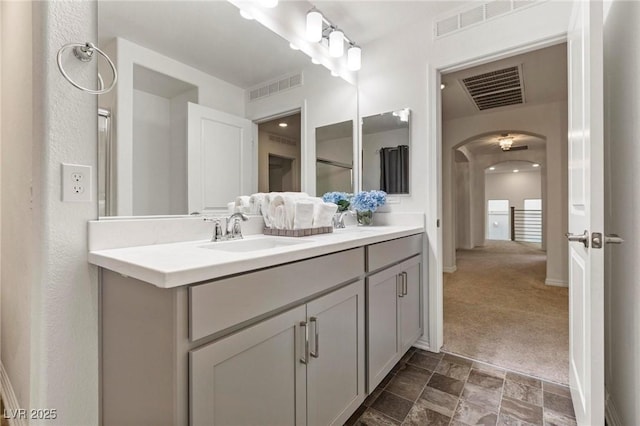 full bath featuring stone finish floor, vanity, and visible vents