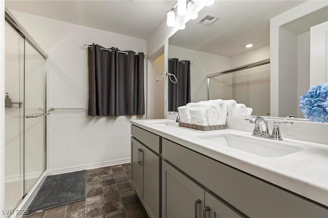 bathroom with double vanity, a shower stall, visible vents, and a sink