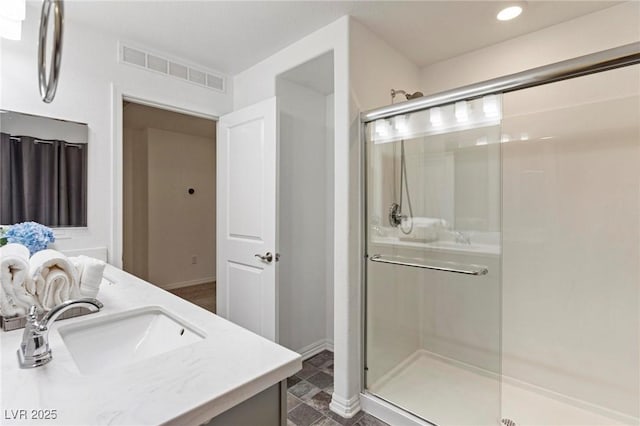 full bath with double vanity, baseboards, visible vents, a shower stall, and a sink