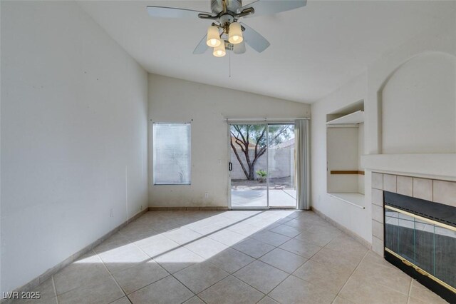 unfurnished living room featuring a fireplace, lofted ceiling, light tile patterned flooring, ceiling fan, and baseboards