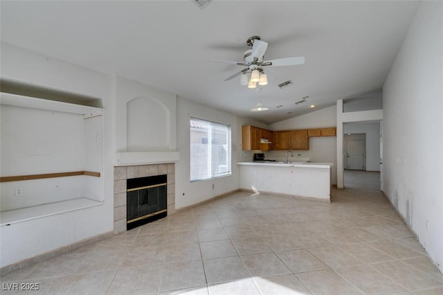 unfurnished living room featuring light tile patterned floors, visible vents, a tiled fireplace, a ceiling fan, and vaulted ceiling