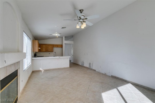unfurnished living room with light tile patterned floors, lofted ceiling, visible vents, ceiling fan, and a tile fireplace