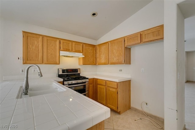 kitchen featuring range with two ovens, tile counters, lofted ceiling, a sink, and under cabinet range hood