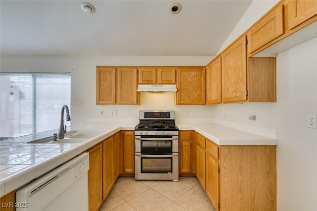 kitchen with range with two ovens, light tile patterned floors, white dishwasher, a sink, and under cabinet range hood