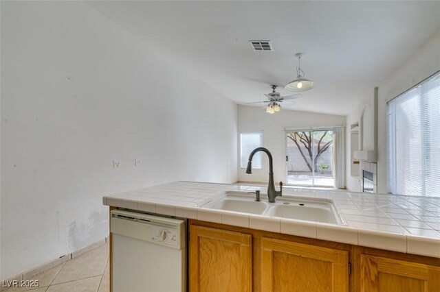 kitchen featuring visible vents, dishwasher, brown cabinets, a sink, and light tile patterned flooring