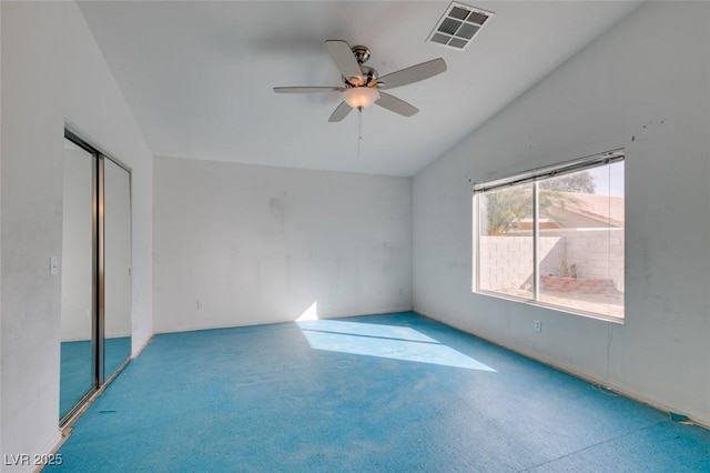 carpeted spare room featuring lofted ceiling, ceiling fan, and visible vents