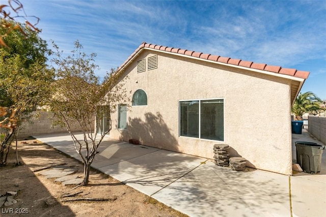 rear view of house with stucco siding, a fenced backyard, and a patio