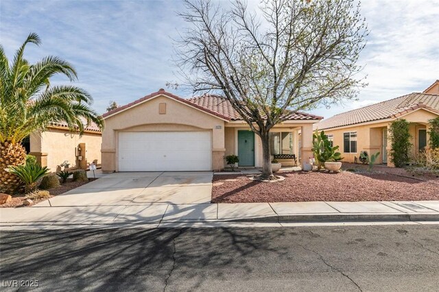 mediterranean / spanish-style house featuring an attached garage, a tiled roof, concrete driveway, and stucco siding