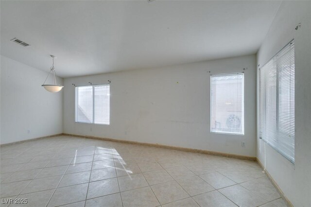 empty room with light tile patterned floors, visible vents, and baseboards