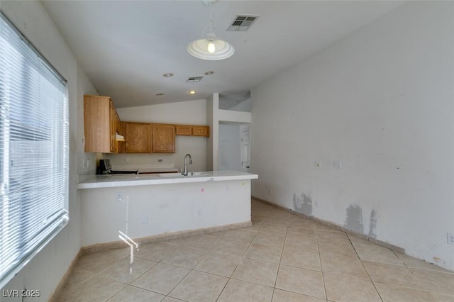 kitchen featuring light tile patterned floors, a peninsula, a sink, visible vents, and vaulted ceiling