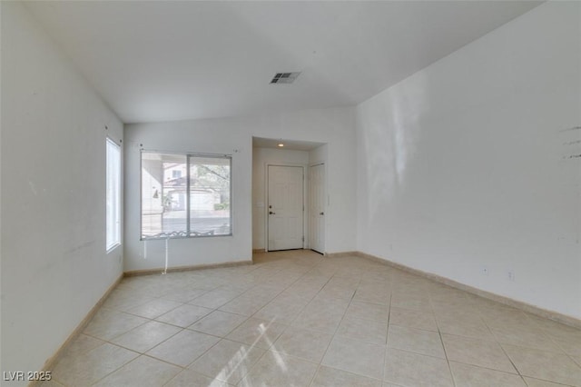 spare room with lofted ceiling, visible vents, baseboards, and light tile patterned flooring