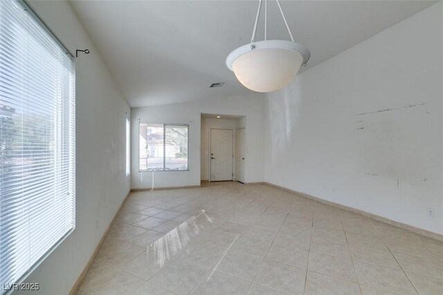 spare room with light tile patterned floors, vaulted ceiling, visible vents, and baseboards
