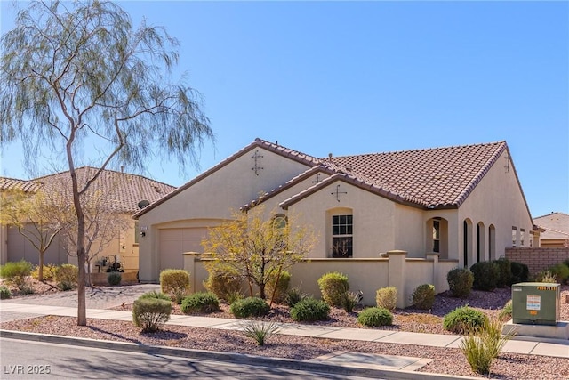 mediterranean / spanish-style home with a fenced front yard, a tiled roof, an attached garage, and stucco siding