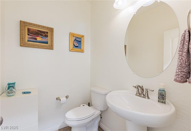 half bathroom with a sink, toilet, and baseboards