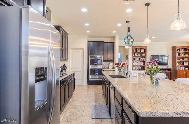 kitchen featuring a spacious island, light stone counters, stainless steel appliances, a sink, and recessed lighting