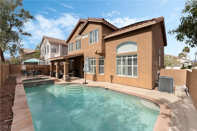 rear view of house with a patio, a fenced backyard, cooling unit, a pool with connected hot tub, and stucco siding