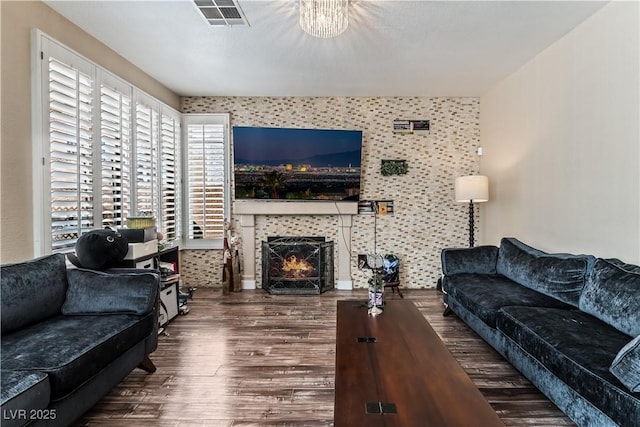 living area with a lit fireplace, visible vents, and dark wood-type flooring