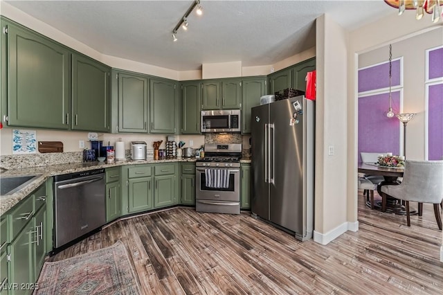 kitchen with green cabinets, stainless steel appliances, and wood finished floors