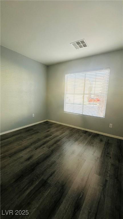 spare room with visible vents, dark wood finished floors, and baseboards