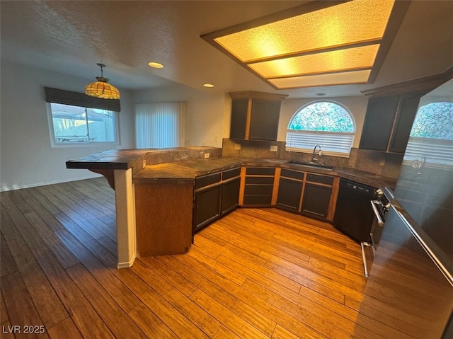 kitchen featuring a peninsula, a sink, a wealth of natural light, and light wood-style floors