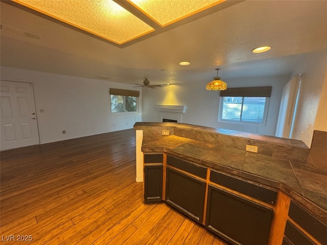 kitchen featuring light wood finished floors, visible vents, tile countertops, open floor plan, and a fireplace