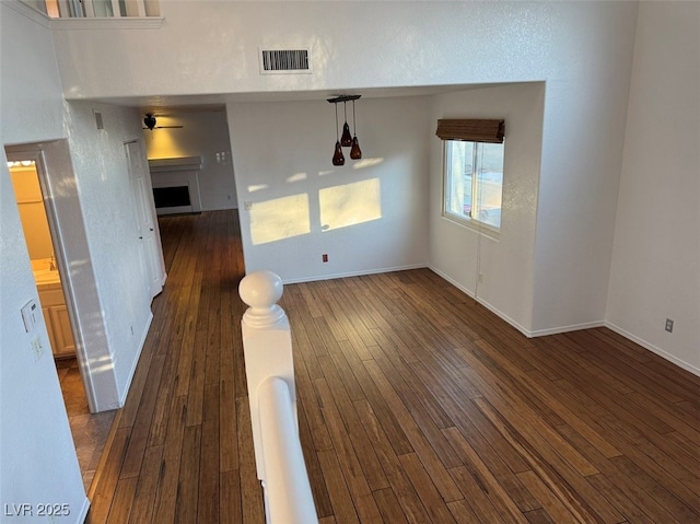 spare room with dark wood-type flooring, a fireplace, visible vents, and baseboards