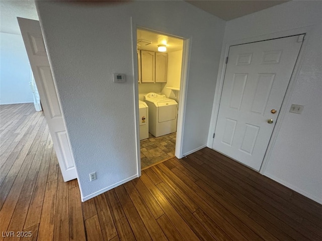 interior space featuring independent washer and dryer, baseboards, and wood finished floors