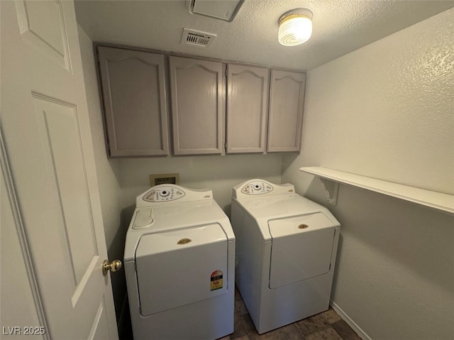 laundry area featuring cabinet space, visible vents, washer and clothes dryer, and a textured ceiling