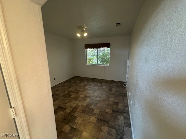 unfurnished room with a textured wall and visible vents