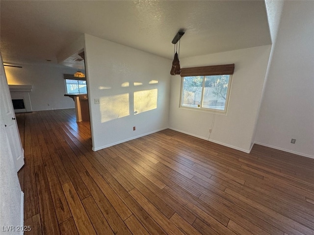 interior space featuring a textured ceiling, a fireplace, baseboards, and dark wood-style flooring