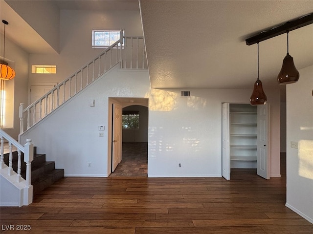 interior space featuring a high ceiling, wood finished floors, visible vents, and baseboards