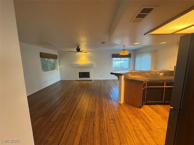 kitchen with a fireplace, light wood finished floors, visible vents, freestanding refrigerator, and open floor plan