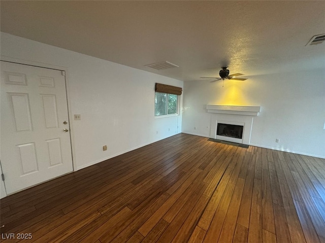 unfurnished living room with a ceiling fan, a fireplace, visible vents, and dark wood-type flooring