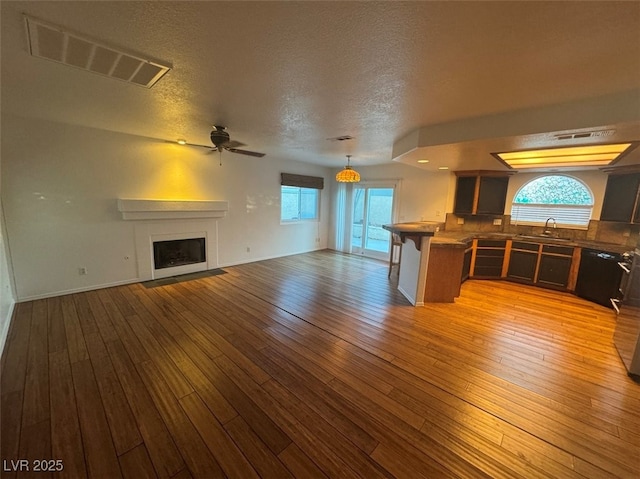 unfurnished living room with light wood-style flooring, visible vents, and a sink