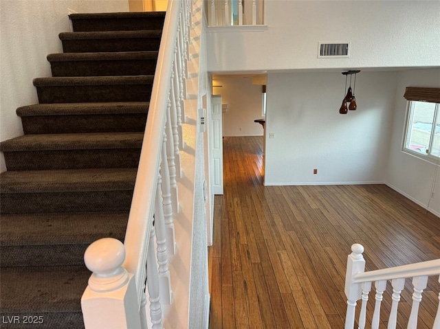 stairway featuring wood finished floors, visible vents, and baseboards