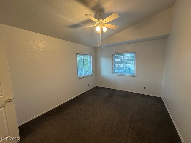 unfurnished room with vaulted ceiling, ceiling fan, dark carpet, and baseboards