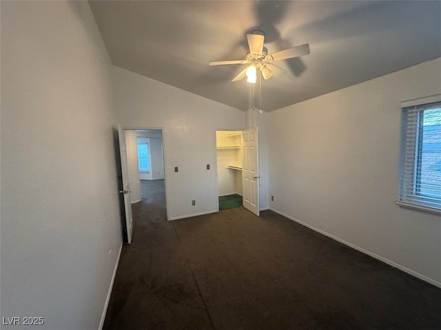 unfurnished bedroom with vaulted ceiling, ceiling fan, dark carpet, and baseboards