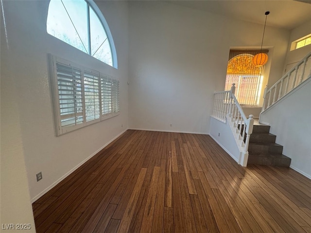 unfurnished living room featuring stairs, high vaulted ceiling, and wood finished floors