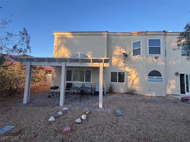 back of house featuring a patio, a pergola, and stucco siding