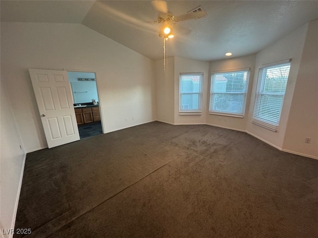 unfurnished room with baseboards, a ceiling fan, lofted ceiling, a textured ceiling, and dark carpet