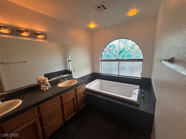 full bath featuring visible vents, a sink, a garden tub, and double vanity