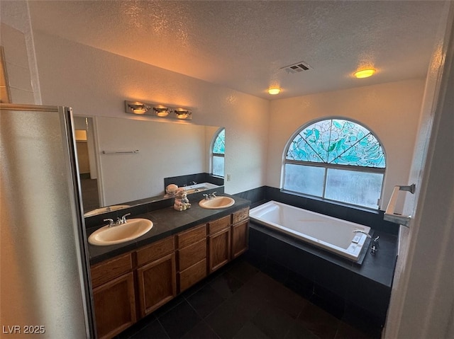 full bath featuring visible vents, a sink, a textured ceiling, and a bath