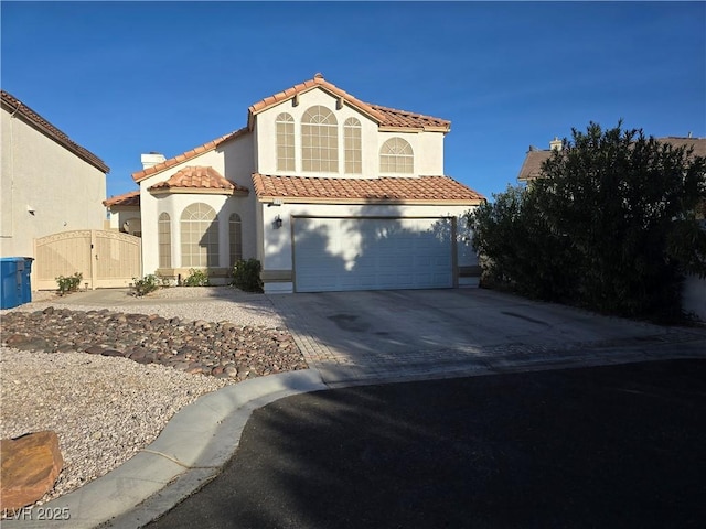 mediterranean / spanish home with a tile roof, stucco siding, a gate, a garage, and driveway