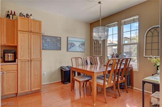 dining space featuring baseboards, light wood-style flooring, and an inviting chandelier