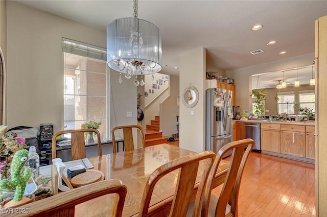 dining space featuring visible vents, light wood-style flooring, stairs, a chandelier, and recessed lighting