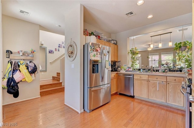 kitchen featuring stainless steel appliances, visible vents, light countertops, and decorative light fixtures